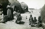 (Foto einer Gruppe Frauen und Kinder vor einigen Hütten) 